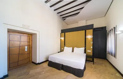 a bedroom with a white bed and a wooden door at Hotel Palacio Marqués de Arizón in Sanlúcar de Barrameda