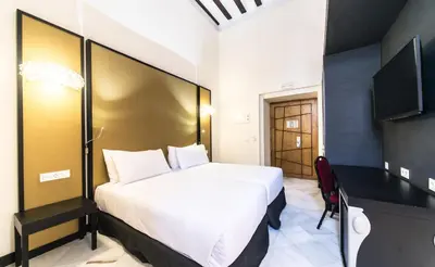 a bedroom with a large white bed and a desk at Hotel Palacio Marqués de Arizón in Sanlúcar de Barrameda