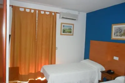 a bedroom with two beds and an orange curtain at Hostal Villa in Chiclana de la Frontera