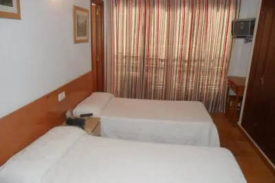 a hotel room with two beds and a window at Hostal Villa in Chiclana de la Frontera