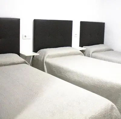 a group of three beds in a room at Hostal Villa in Chiclana de la Frontera