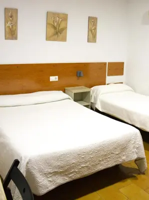a hotel room with two beds and paintings on the wall at Hostal Villa in Chiclana de la Frontera