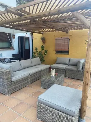a patio with couches and tables and a wooden pergola at Casa Rural Los Pepe Sancti Petri in Chiclana de la Frontera