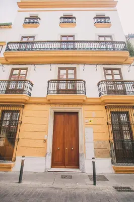 a building with a wooden door and two balconies at Apartamentos casa palacio in El Puerto de Santa María