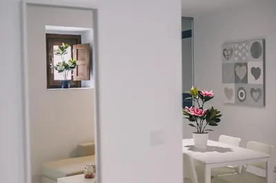a white room with a table with flowers on it at Apartamentos casa palacio in El Puerto de Santa María