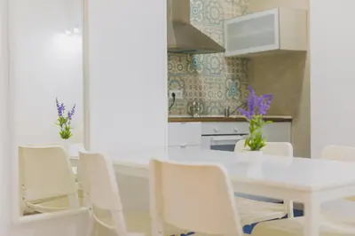 a white kitchen with a white table and chairs at Apartamentos casa palacio in El Puerto de Santa María