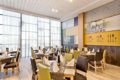 a dining room with tables and chairs and windows at Hotel Best Costa Ballena in Costa Ballena