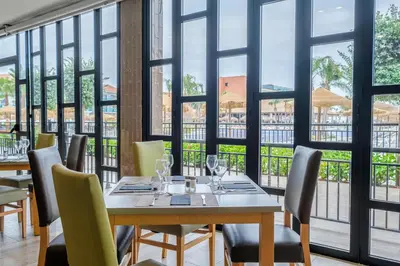 a dining room with a table and chairs and windows at Hotel Best Costa Ballena in Costa Ballena