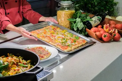 a person holding a pan of pizza on a counter at Hotel Best Costa Ballena in Costa Ballena