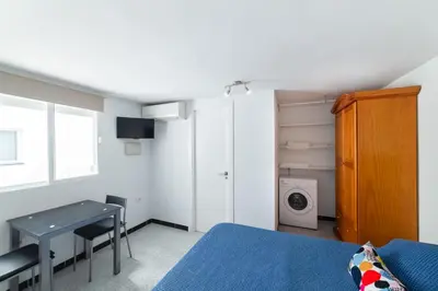 a bedroom with a bed and a table and a washing machine at Coqueto estudio in Cádiz