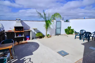 a patio with a grill and tables and chairs at Casa Manoli in Conil de la Frontera