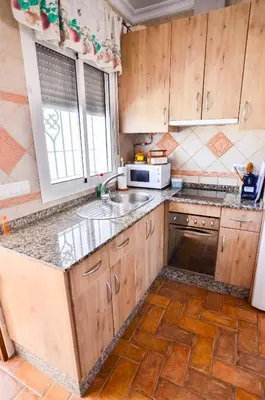a kitchen with wooden cabinets and a sink and a microwave at Casa Manoli in Conil de la Frontera