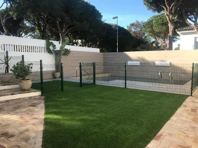 a fence with green grass in a yard at Villa Chill In in Chiclana de la Frontera