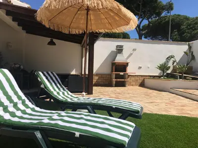 two green and white chairs under an umbrella at Villa Chill In in Chiclana de la Frontera