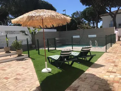 a patio with two chairs and a straw umbrella at Villa Chill In in Chiclana de la Frontera