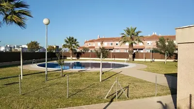 a pool in a park with palm trees and a building at Apartamento Estrella in Sanlúcar de Barrameda