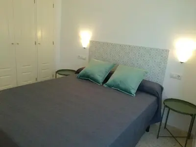 a bedroom with a bed with two green pillows at Apartamento Estrella in Sanlúcar de Barrameda
