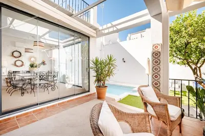 an indoor patio with wicker chairs and a dining room at Casa palacio reformada S.XVIII in Sanlúcar de Barrameda