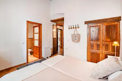 a bedroom with a white bed and a wooden door at Casa palacio reformada S.XVIII in Sanlúcar de Barrameda