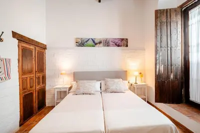 a bedroom with a large white bed with two tables at Casa palacio reformada S.XVIII in Sanlúcar de Barrameda