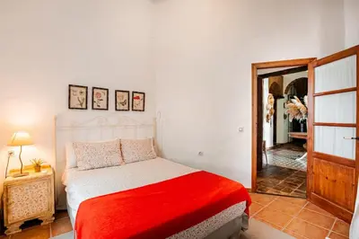 a bedroom with a bed with a red blanket at Casa palacio reformada S.XVIII in Sanlúcar de Barrameda