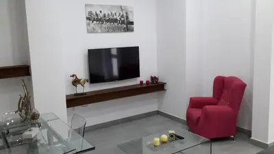 a living room with a red chair and a television at La Pandorga in Sanlúcar de Barrameda