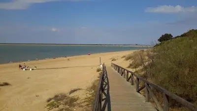 a boardwalk leading to a beach with people on it at La Pandorga in Sanlúcar de Barrameda