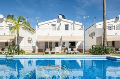 a house with a swimming pool in front of a building at Apartamentos Los Olivos in Conil de la Frontera