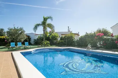 a swimming pool in a yard with two blue chairs at Apartamentos Los Olivos in Conil de la Frontera