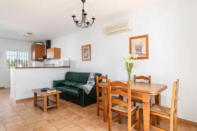 a living room with a table and a green couch at Apartamentos Los Olivos in Conil de la Frontera