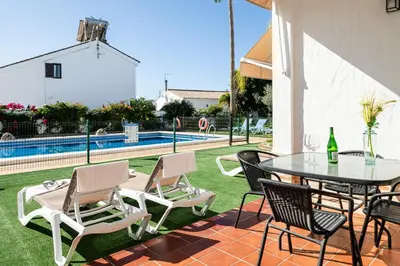 a patio with a table and chairs and a pool at Apartamentos Los Olivos in Conil de la Frontera