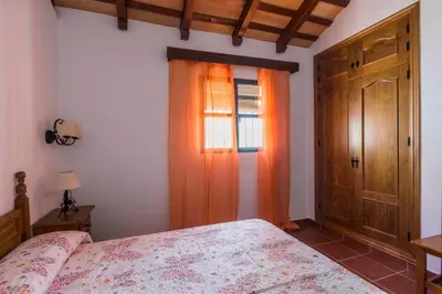 a bedroom with a bed and a window with an orange curtain at Vivienda Rural Atlántico Sur & Familias in Conil de la Frontera