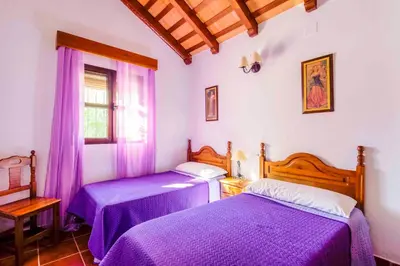 two beds in a bedroom with purple sheets at Vivienda Rural Atlántico Sur & Familias in Conil de la Frontera