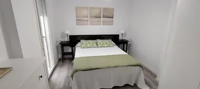 a small bedroom with a bed in a white room at Apto Melkart in Chiclana de la Frontera