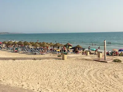a beach with many umbrellas and people on the beach at Apto Melkart in Chiclana de la Frontera
