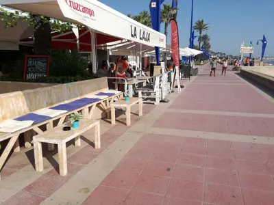 a row of benches on a sidewalk near a beach at Apto Melkart in Chiclana de la Frontera