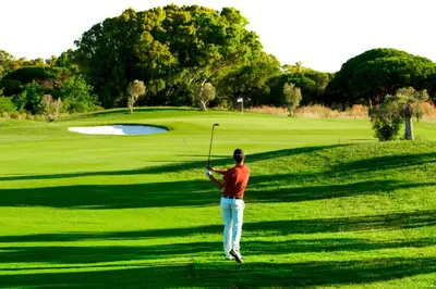 a man swinging a golf club on a golf course at Apto Melkart in Chiclana de la Frontera