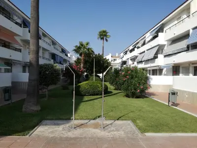 a courtyard of a apartment building with two poles in the grass at Apto Melkart in Chiclana de la Frontera