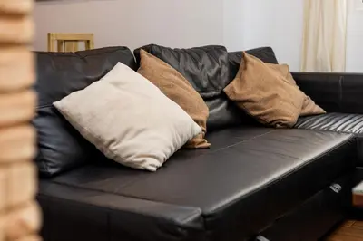 a black leather couch with pillows on it at Casa Plotina Pompeya in Cádiz