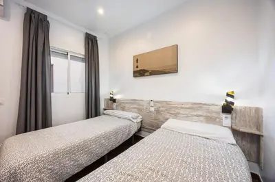 two beds in a room with a window at Casa Plotina Pompeya in Cádiz