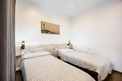 a room with two beds and a picture on the wall at Casa Plotina Pompeya in Cádiz