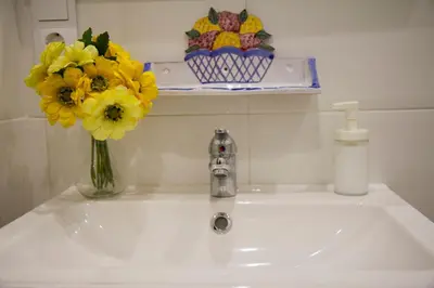 a bathroom sink with a vase of yellow flowers on it at Infanta Beatriz in Sanlúcar de Barrameda