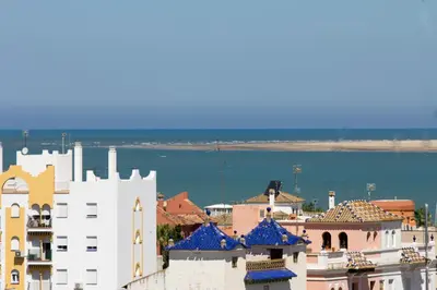 a group of buildings with the ocean in the background at Infanta Beatriz in Sanlúcar de Barrameda