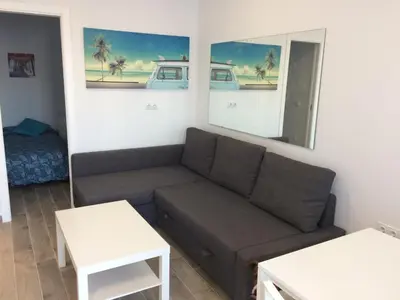 a living room with a couch and a mirror at Apartamento faro Puerto Sherry in El Puerto de Santa María