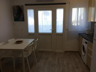 a kitchen and dining room with a table and a door at Apartamento faro Puerto Sherry in El Puerto de Santa María