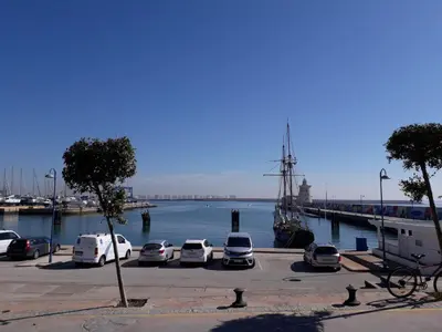 a group of cars parked in a parking lot next to a boat at Apartamento faro Puerto Sherry in El Puerto de Santa María
