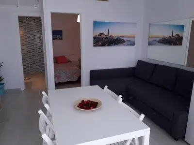 a living room with a white table and a couch at Apartamento faro Puerto Sherry in El Puerto de Santa María