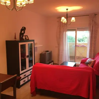 a living room with a red bed and a tv at Playa de Las Piletas in Sanlúcar de Barrameda