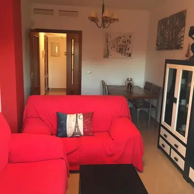 a red couch in a living room with a table at Playa de Las Piletas in Sanlúcar de Barrameda