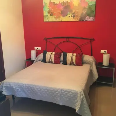 a bedroom with a bed with a red wall at Playa de Las Piletas in Sanlúcar de Barrameda